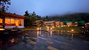 A courtyard with a fire pit, outdoor seating, and multiple wooden cabins. - The Tiger Nest Camp (Paro)