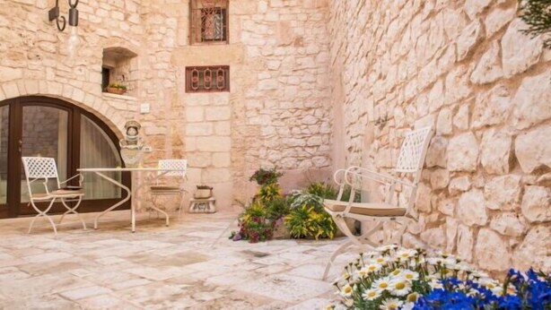 A stone-walled courtyard with a table and chairs, a bench, and a small altar. - Dimora dell'Osanna  (Carovigno)