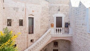 A stone building with a balcony, a staircase, and a small window with a curtain. - Dimora dell'Osanna  (Carovigno)