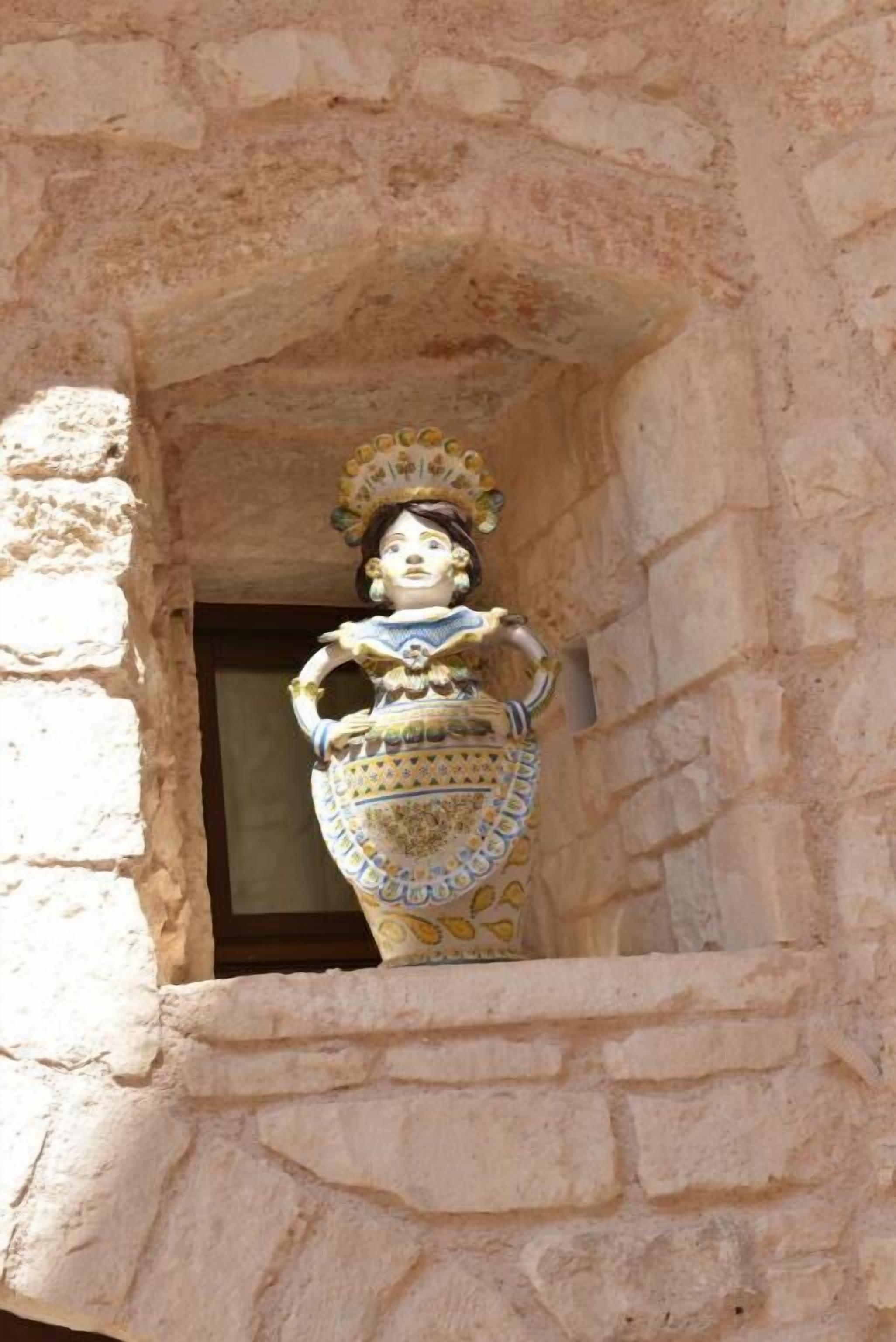 A statue in a niche with a stone wall.