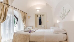 A bedroom with a large bed, a bathroom with a towel rack, and a view of the outdoors. - Dimora dell'Osanna  (Carovigno)