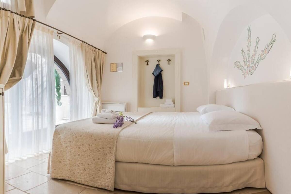 Un dormitorio con una cama grande, un baño con toallero y vistas al exterior.