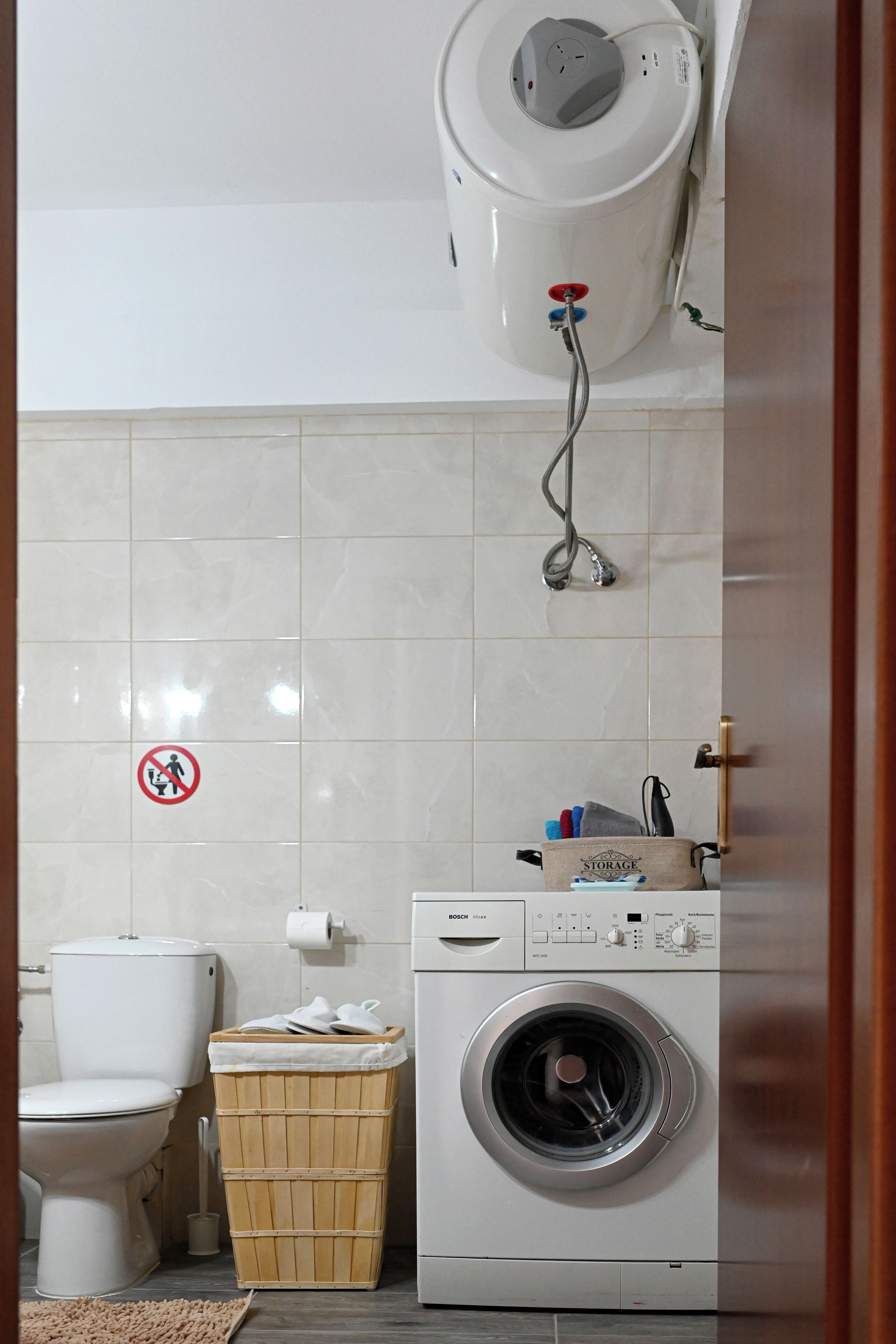 A bathroom with a toilet, a washing machine, and a water heater.