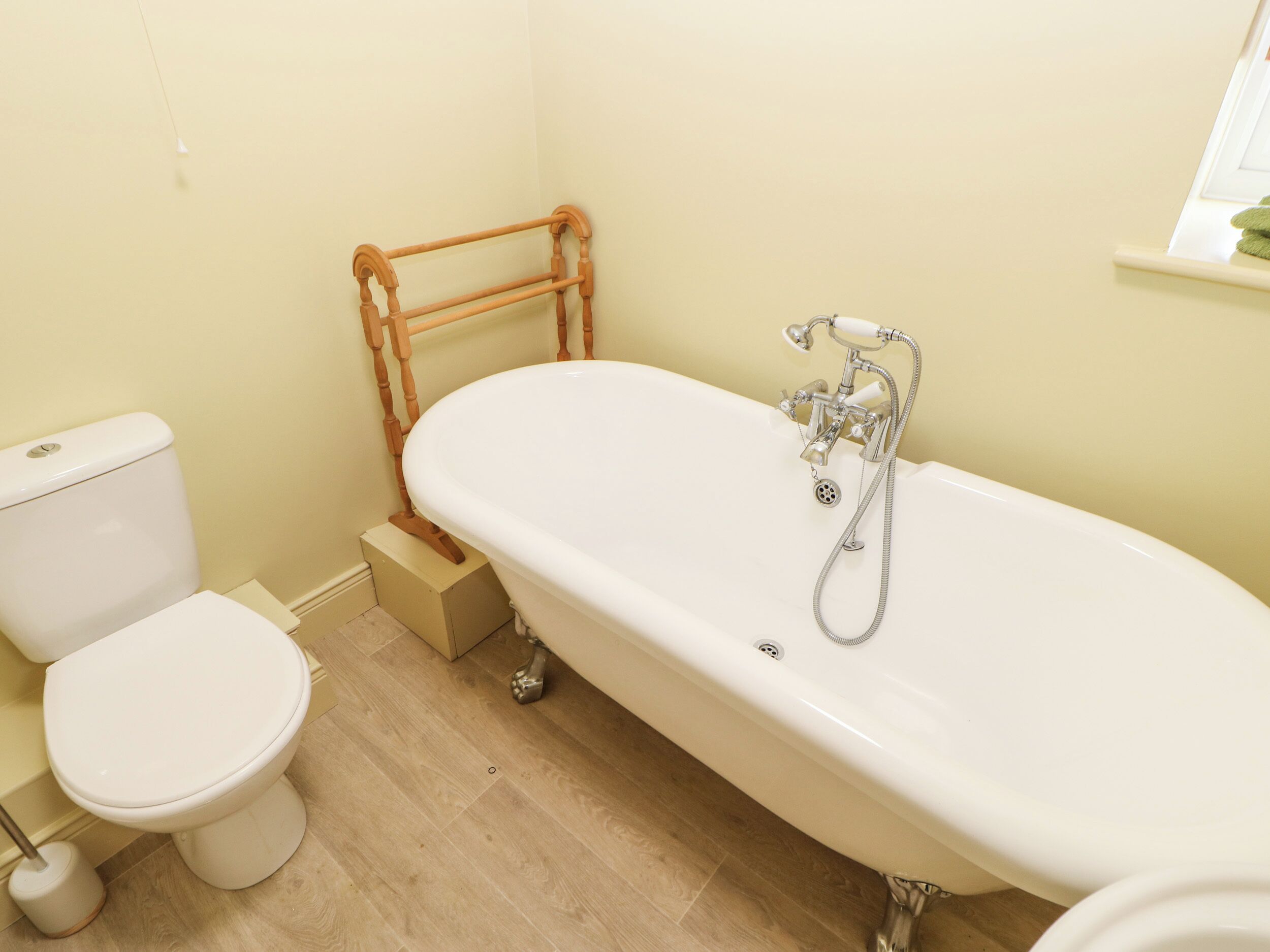 Un baño con una bañera blanca, un inodoro y una escalera de madera para la ducha.