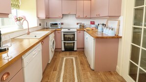 Une cuisine compacte avec des placards roses, un four à micro-ondes, un grille-pain, un lave-linge et un lave-vaisselle.