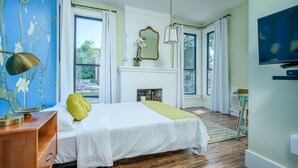 A bedroom with a bed, a dresser, a mirror, a fireplace, and a television. - Private Suite in Historic Austin B&b: Sleeps 2! (Austin)