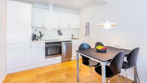 Une cuisine moderne avec des meubles blancs, un lave-vaisselle et un coin repas comprenant une table et des chaises.