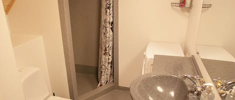 A compact bathroom with a toilet, sink, and shower.