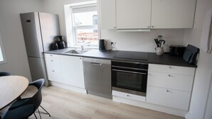 A modern kitchen with white cabinets, a dishwasher, an oven, and a coffee maker. - In The Heart Of Tórshavn Nr1 (Tórshavn)
