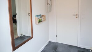 A hallway with a large mirror, a white door, and a small shelf with items. - In The Heart Of Tórshavn Nr1 (Tórshavn)