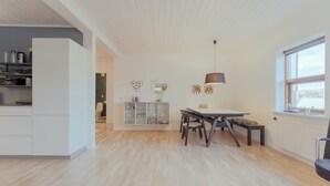 A modern kitchen with white cabinetry, a dining area with a table and chairs, and a large window with a view.