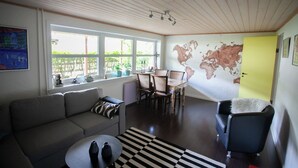 A living room with a sofa, dining table, chairs, and a map mural on the wall.