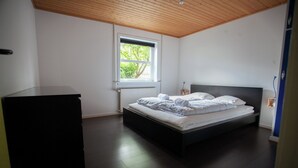 A bedroom with a bed, a window, and a dresser.