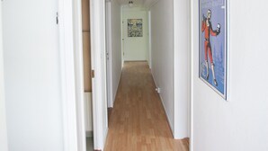 A hallway with wooden flooring, white walls, and a poster of a historical figure.