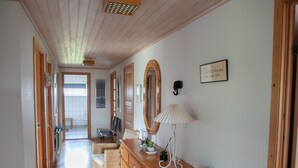 Un couloir avec un plancher en bois, une commode en bois, une lampe et une plante en pot.