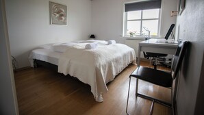 Une chambre à coucher avec un lit, un bureau, une chaise et une fenêtre.
