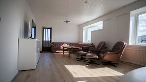 A spacious living room with a large window, a sofa, two armchairs, and a coffee table. - The Bird / Guesthouse / 10 Min Walk Downtown (Tórshavn)