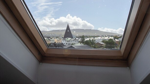 A skylight with a view of a town, including a church and houses. - The Bird / Guesthouse / 10 Min Walk Downtown (Tórshavn)