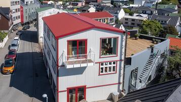 A multi-story hotel with a red roof, balconies, and a visible ground floor entrance.