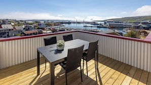 A wooden deck with a table and chairs, overlooking a marina with boats and buildings. - Downtown - Retro Decor - Stunning Views - Terrace (Tórshavn)