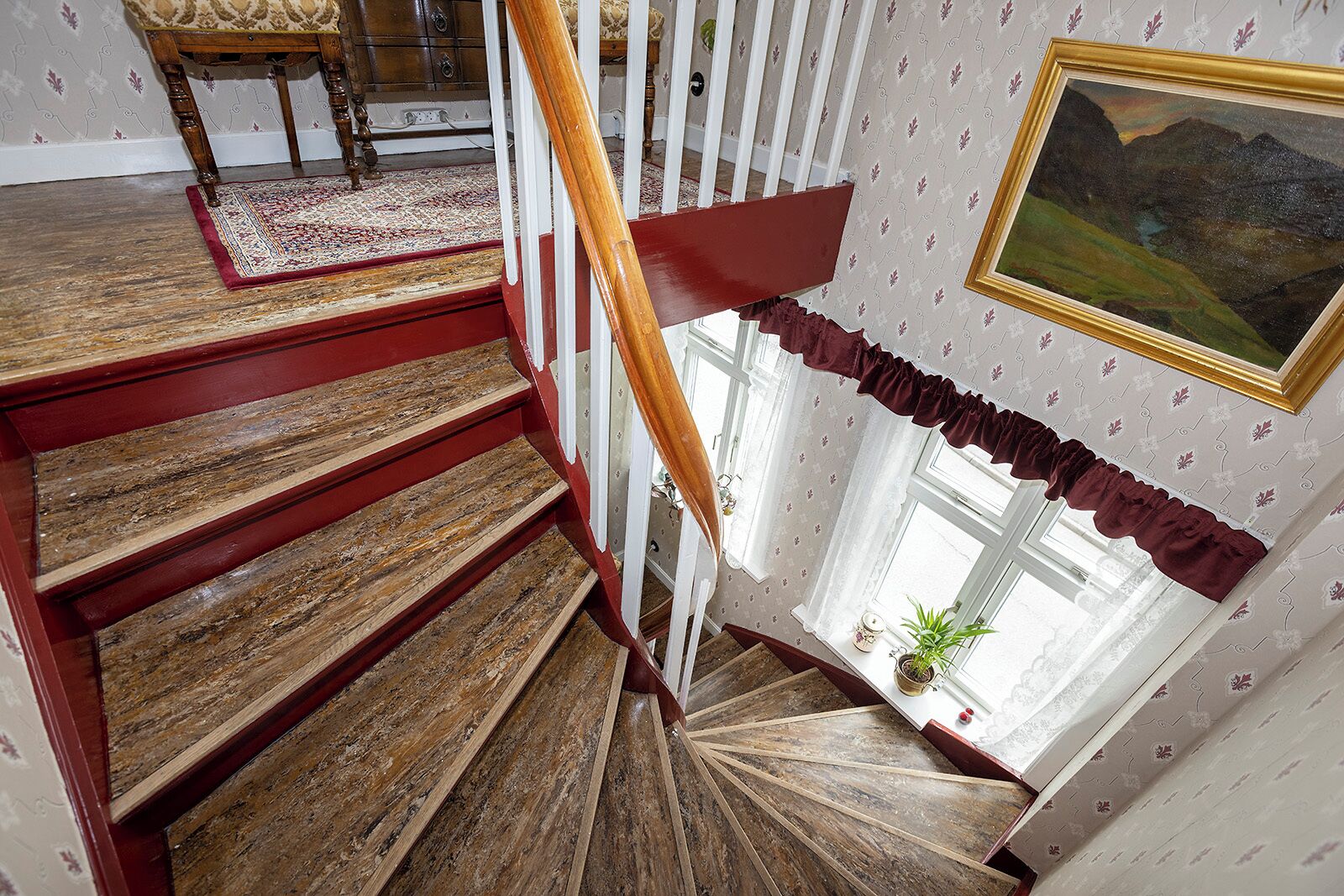 Un escalier en bois avec une rampe rouge menant à un palier.