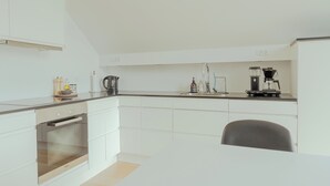 A modern kitchen with white cabinetry, a built-in oven, a coffee machine, and a sink. - Stunning Views / Penthouse / Decorative / Parking (Nykobing Sjaelland)