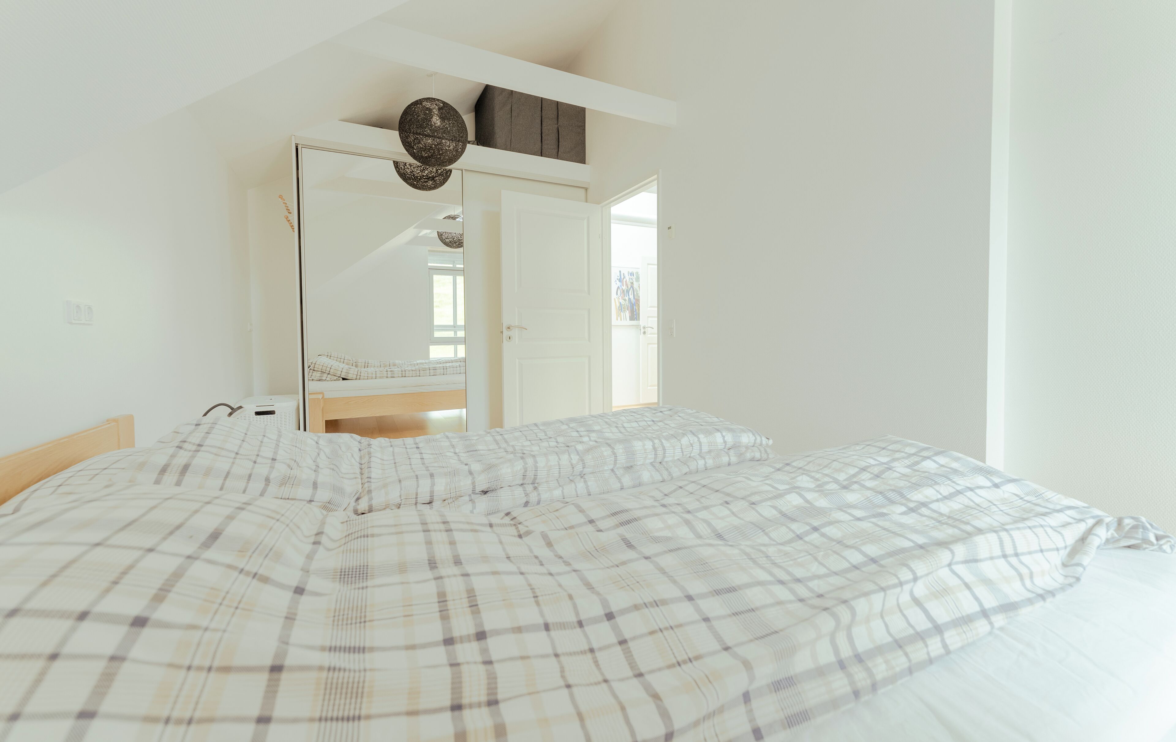 A bedroom with a bed, a wardrobe, and a door leading to another room.