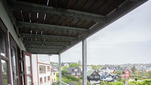 A wooden balcony with a view of houses and greenery. - Aparthotel - Marina - Central - Tórshavn (Tórshavn)