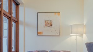 A modern living room with a grey sofa, a white coffee table, a floor lamp, and a framed abstract painting on the wall. - Aparthotel - Marina - Central - Tórshavn (Tórshavn)