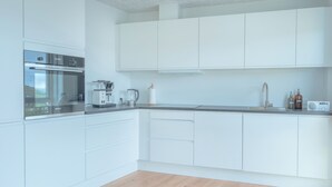 A modern kitchen with white cabinetry, a built-in oven, a coffee maker, and a radio.