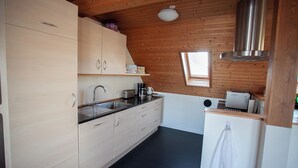 A compact kitchen with wooden walls, a black countertop, and a stainless steel range hood. - Tórshavn - Central - City & Ocean Views - 3Br (Tórshavn)