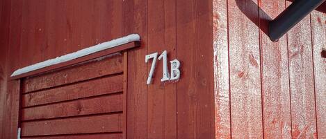 Un edificio de madera rojo con una puerta de garaje y el número 71B.