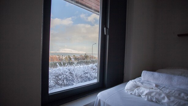 A room with a bed and a window overlooking a snowy landscape. - Large Apartment With Fabulous View Of Tórshavn (Tórshavn)