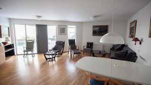 A spacious living area with a wooden floor, a dining table, and multiple seating options including a sofa and chairs. - Large Apartment With Fabulous View Of Tórshavn (Tórshavn)