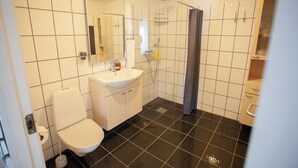 A bathroom with a toilet, sink, mirror, shower, and tiled walls. - Large Apartment With Fabulous View Of Tórshavn (Tórshavn)