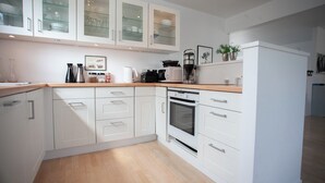A modern kitchen with white cabinetry, a built-in oven, and a coffee maker.