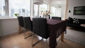 A modern dining area with a table, chairs, and a vase of flowers.