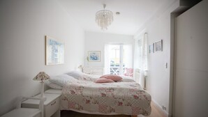 A bedroom with a bed, a nightstand, a lamp, and a chandelier.