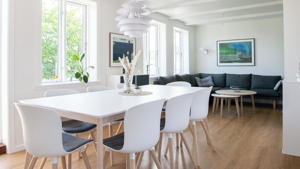 Ein geräumiges Wohnzimmer mit Essbereich, großen Fenstern und einem modernen Kronleuchter.