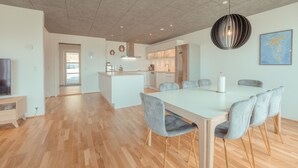 A modern kitchen with a central island, a dining area with a large table and chairs, and a view of the living room. - Breathtaking Views - New - 220M2 - 5 Br - Walks (Argir)