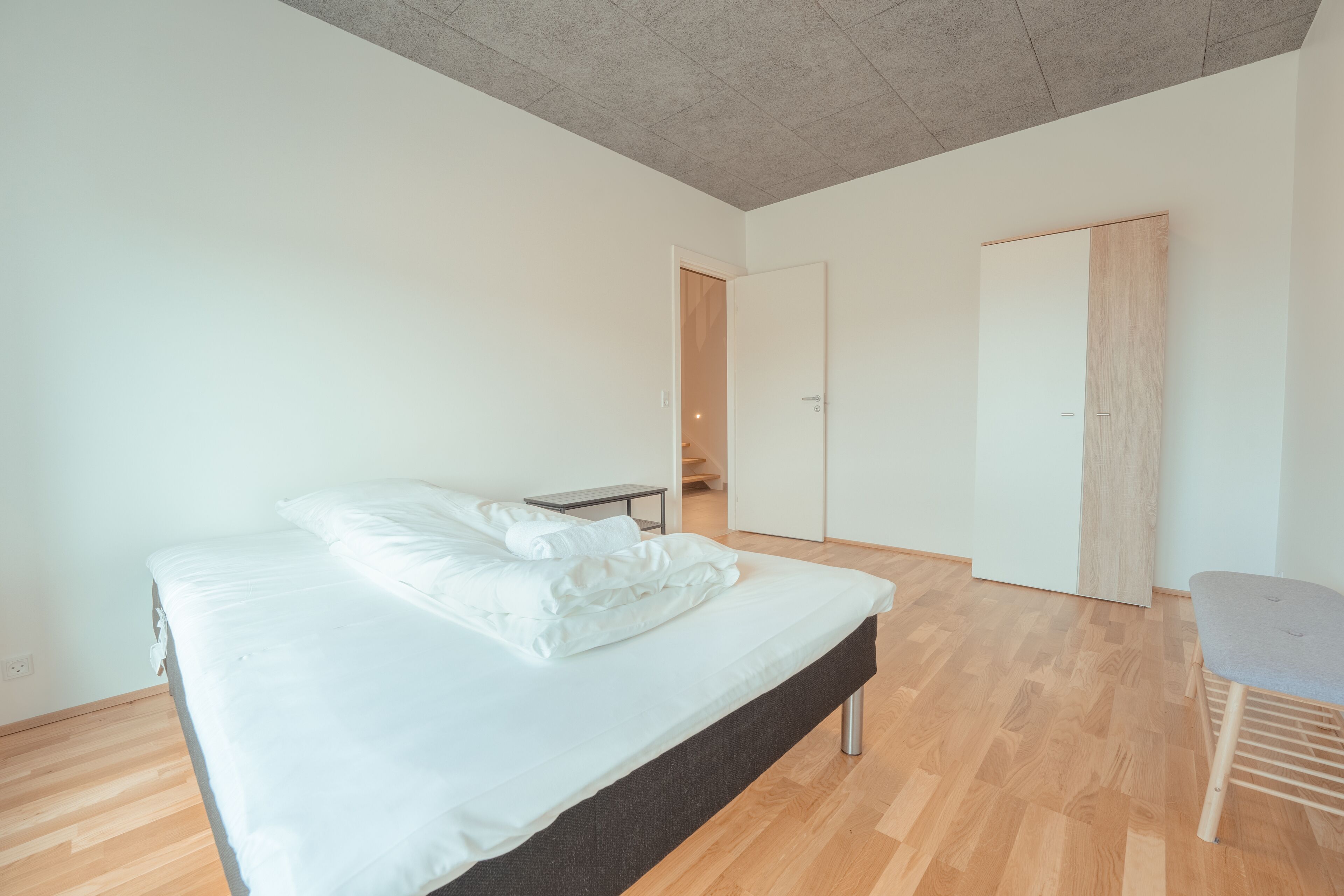 A bedroom with a bed, a small table, a chair, and a wardrobe.