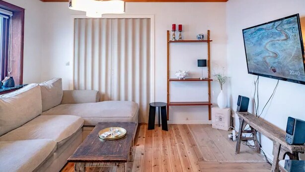 A modern living room with a sofa, a wooden coffee table, a TV, and a shelf with decorative items. - 3 Bedroom Apartment / Great Sea View / Quiet (Argir)