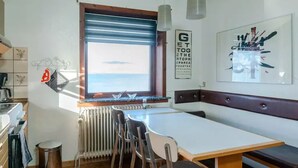 A kitchen with a dining area, a window with blinds, a radiator, and a bench. - 3 Bedroom Apartment / Great Sea View / Quiet (Argir)