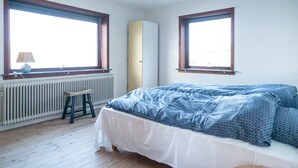 A bedroom with a bed, a radiator, a window, and a stool. - 3 Bedroom Apartment / Great Sea View / Quiet (Argir)