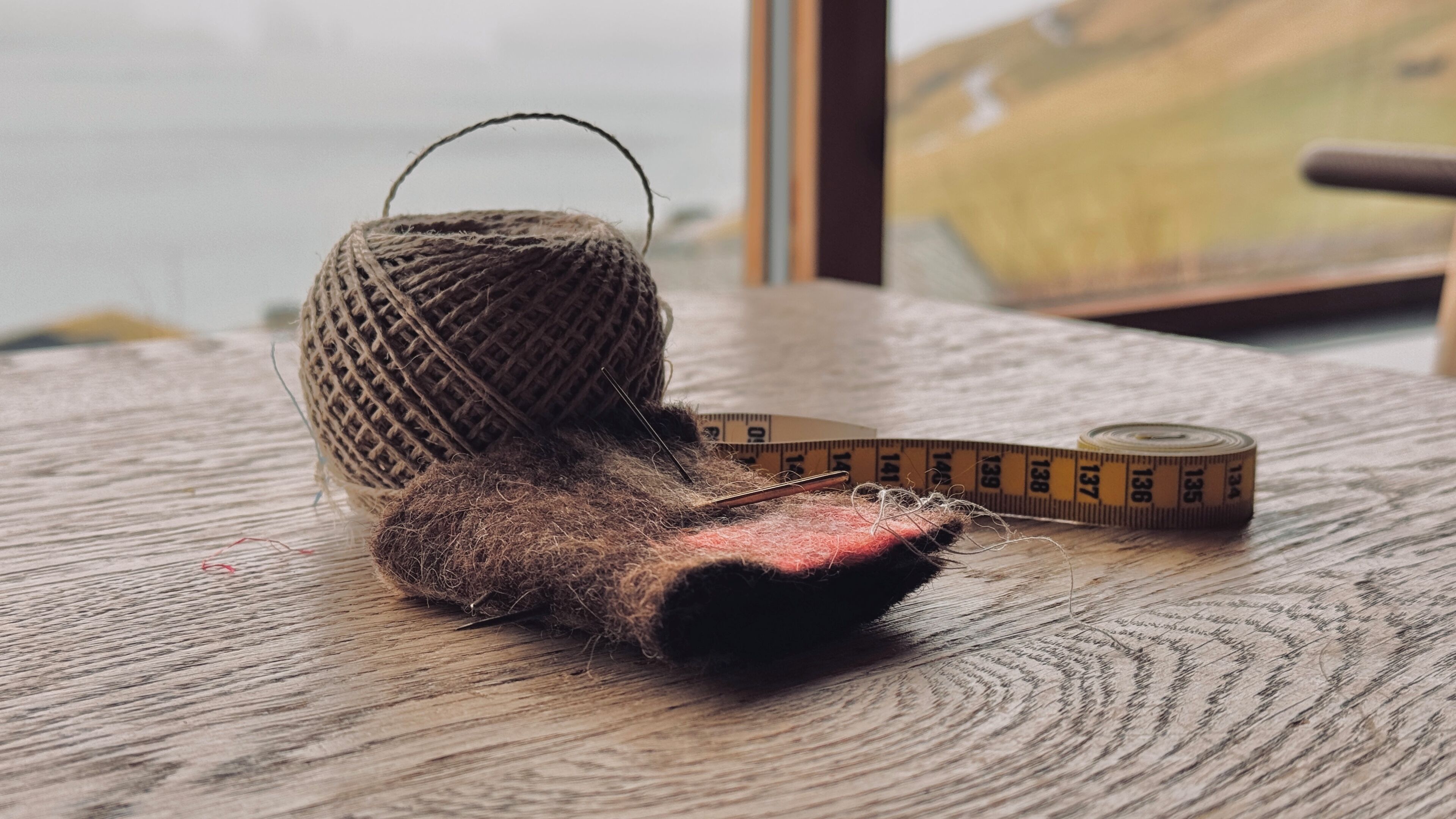 A rustic wooden table with a measuring tape and a ball of twine.