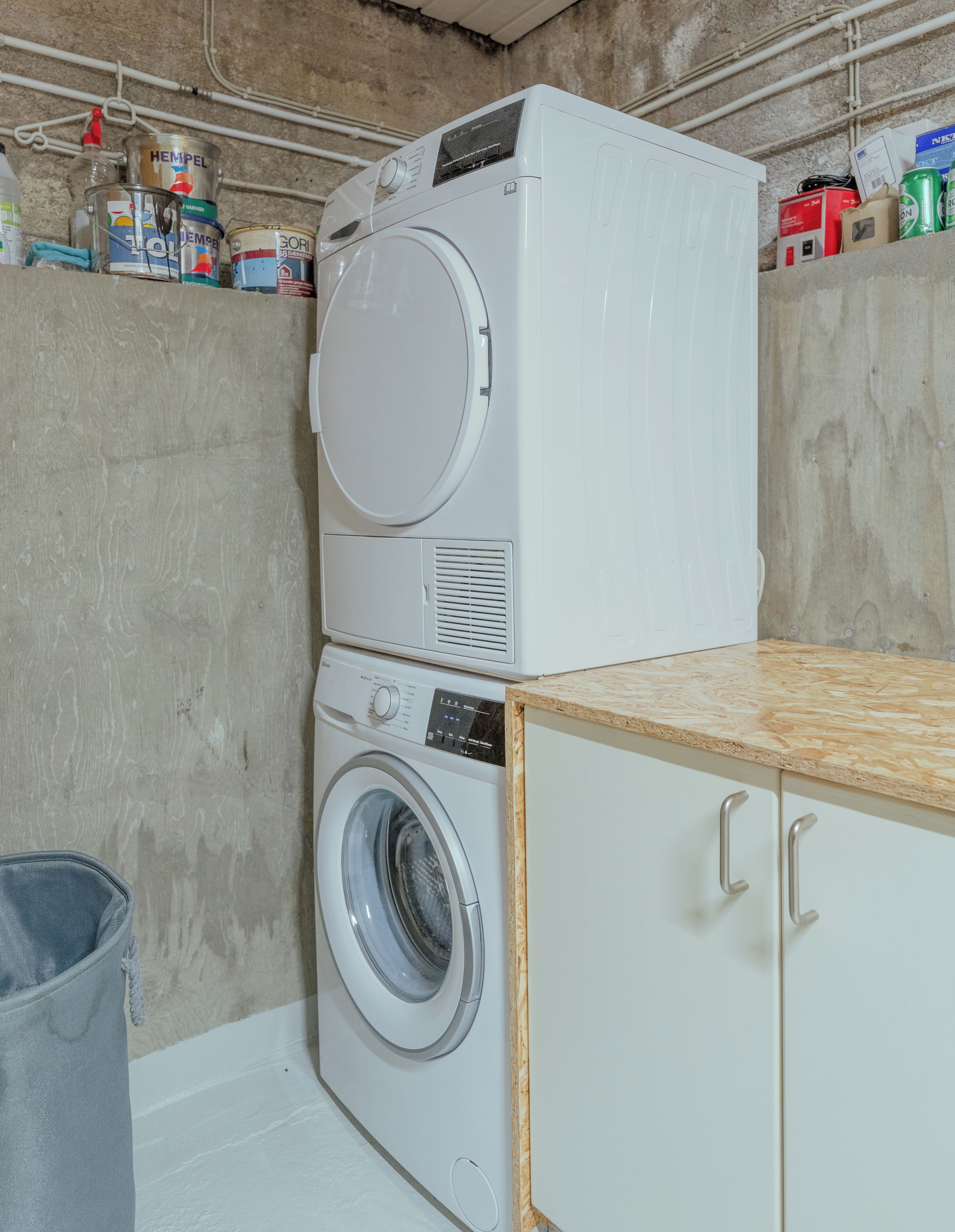 A laundry area with stacked washing machines and a drying rack.