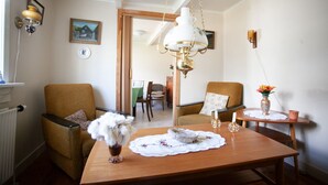 A dining area with a wooden table, two chairs, a vase with flowers, and a hanging lamp. - Cozy House In The Idyllic Village Of Haldórsvík (Haldórsvík)