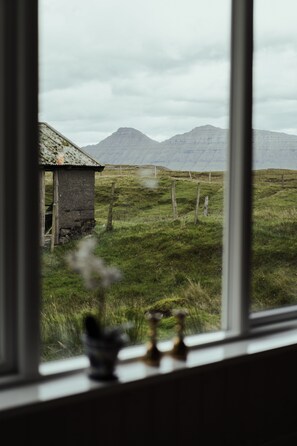 A rustic cabin with a thatched roof, surrounded by a grassy field and mountains in the background. - Authentic Cabin - Unique Location - In Nature - 2Br (Hellurnar)