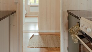 A wooden interior with a kitchen area, a rug, and a view into another room. - Authentic Cabin - Unique Location - In Nature - 2Br (Hellurnar)