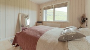 A bedroom with a bed, a window with a view of the outdoors, a mirror, and a bedside lamp. - Authentic Cabin - Unique Location - In Nature - 2Br (Hellurnar)